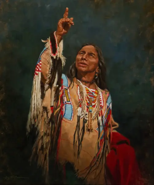 Native American man in colorful ceremonial regalia raises one finger toward the sky, looking up.