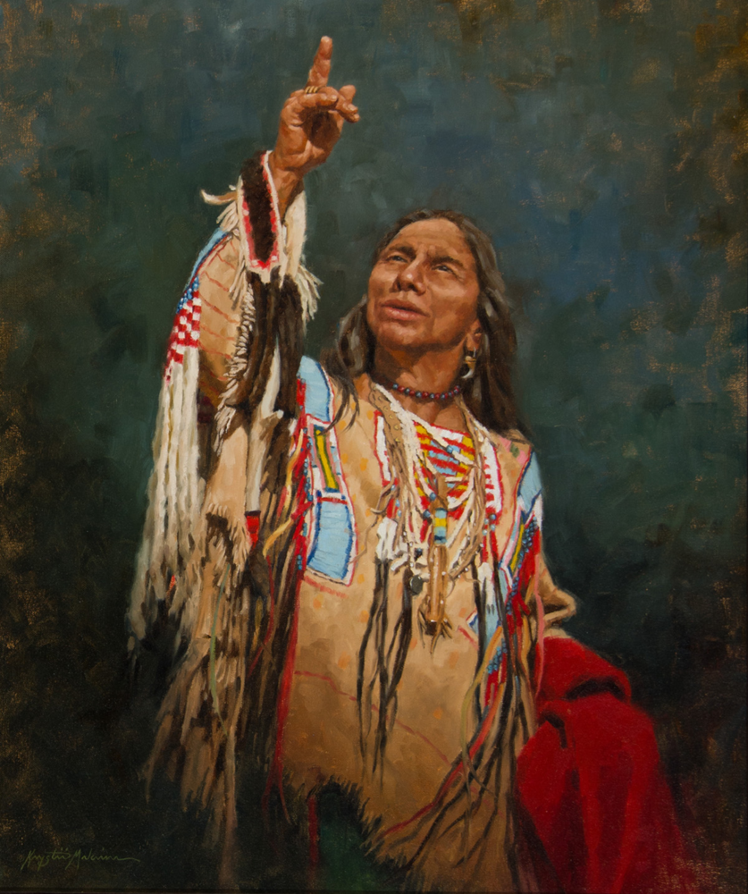 Native American man in colorful beadwork and fringe, raising his right hand with index finger pointing upward.
