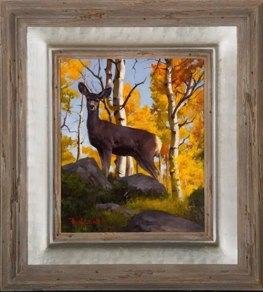 Framed painting of a deer standing on rocks in a fall forest with yellow and orange trees.