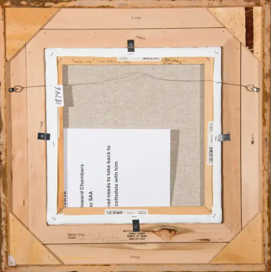 Back of a stretched canvas in a wooden frame, showing hanging wire, labels, and a white paper note partially covering the canvas.