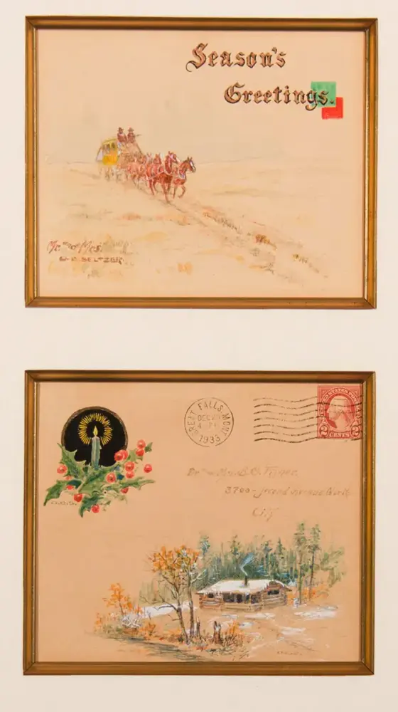 Two framed vintage postcards: top card says 'Season's Greetings' with a horse-drawn sleigh in a snowy landscape; bottom card shows a winter cabin scene with trees and flowers and a decorative sun motif.