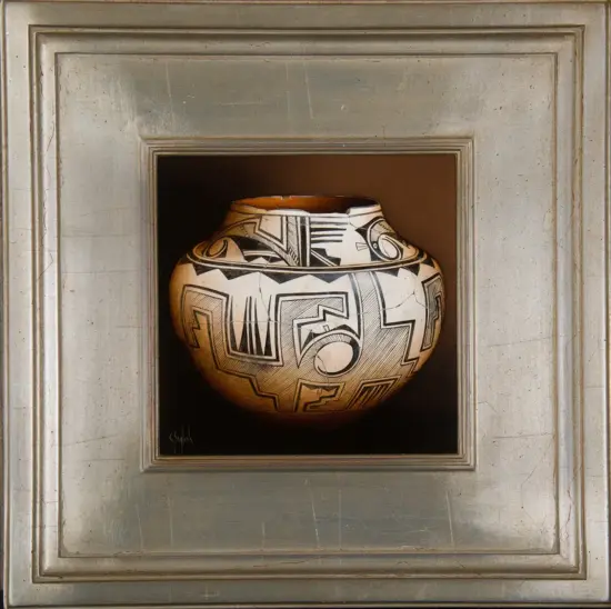 Round ceramic vase with bold black geometric designs on a beige surface, mounted in a recessed frame of a gallery display.