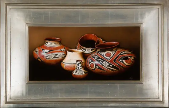 Cluster of red, cream, and black geometric pottery vessels arranged together in a brown display inside a metal-framed niche.