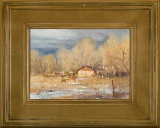 Winter landscape painting: a small cottage among bare trees in a snow-dusted field, under a cloudy sky, housed in a gold ornate frame