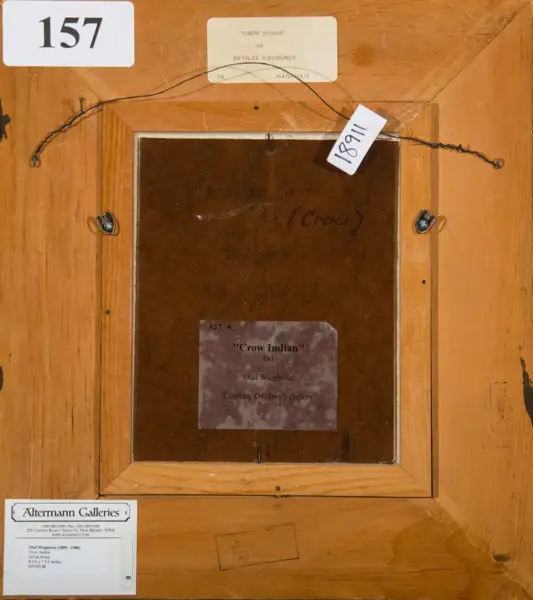 Back of a wooden framed oil painting labeled “Crow Indian” by Olaf Wieghorst, with gallery labels, a hanging wire, and a large white 157 tag at the top.