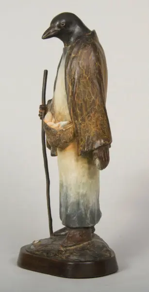 Wooden sculpture of a robed figure with a raven-like head, holding a staff and a woven basket, standing on a round base.