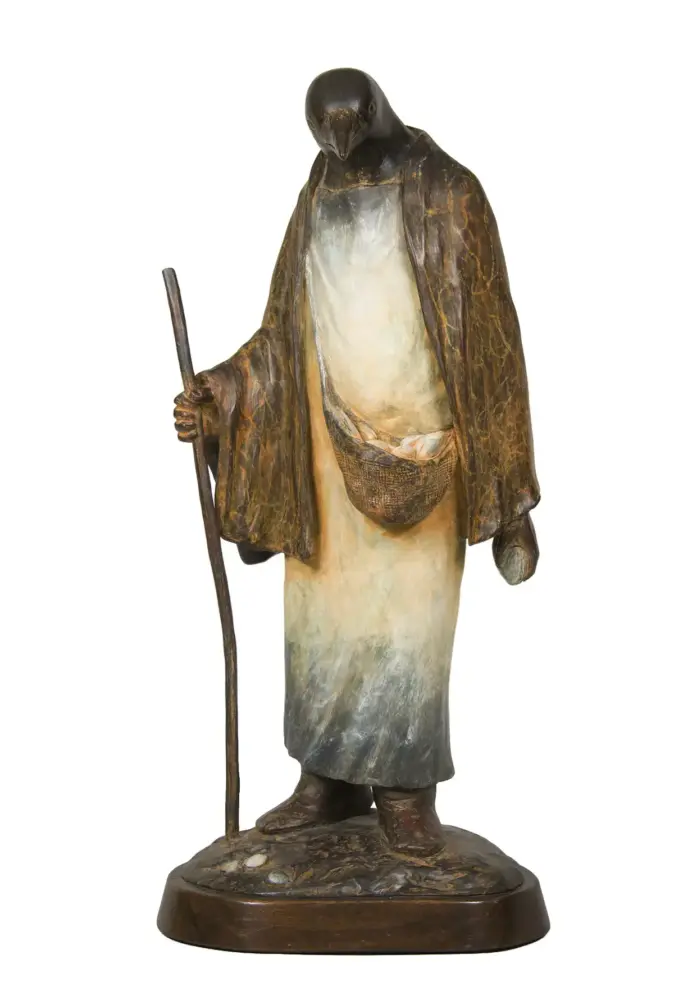 Bronze-toned statue of a robed pilgrim holding a walking staff, with a small belt pouch, standing on a circular base