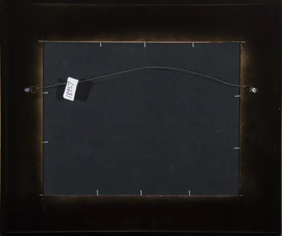 Back of a framed artwork showing a hanging wire with small label attached to the left side.