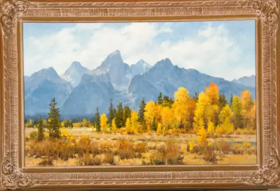 Autumn landscape painting of blue mountains with yellow trees in the foreground, inside an ornate gold frame.