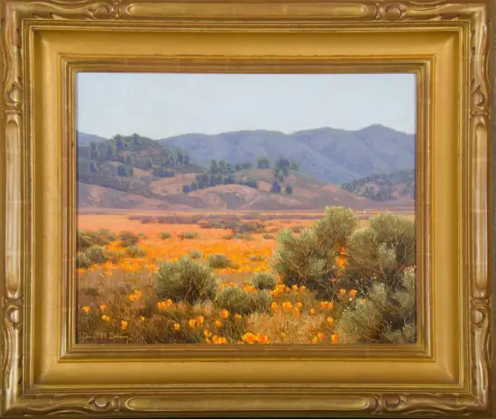 Landscape painting of a desert valley with orange wildflowers in the foreground, sagebrush, and distant blue mountains under a pale sky, in a gold ornate frame on the wall.