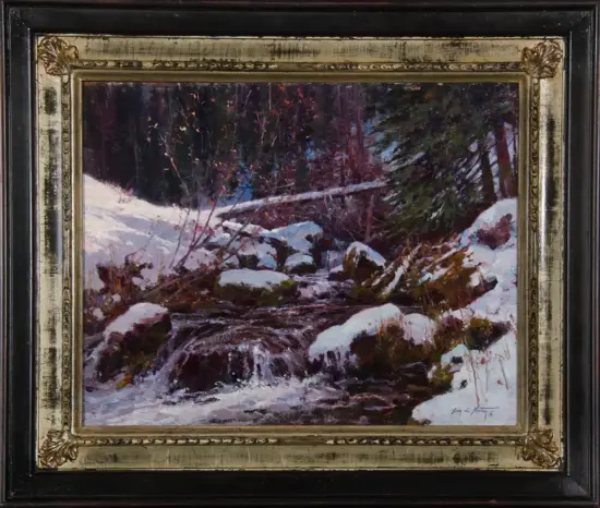 Snowy forest landscape with a rocky, mossy stream winding through snow, framed by dark evergreens in the background.