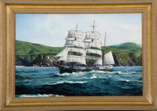 Framed painting of a tall sailing ship on a blue sea with green hills in the background.