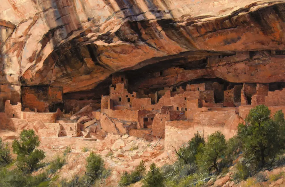 Cliff dwellings built into a red rock alcove under a sandstone overhang, with trees in the foreground.