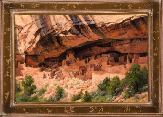 Framed painting of red rock canyon with adobe cliff dwellings under a rock overhang and green trees in front.