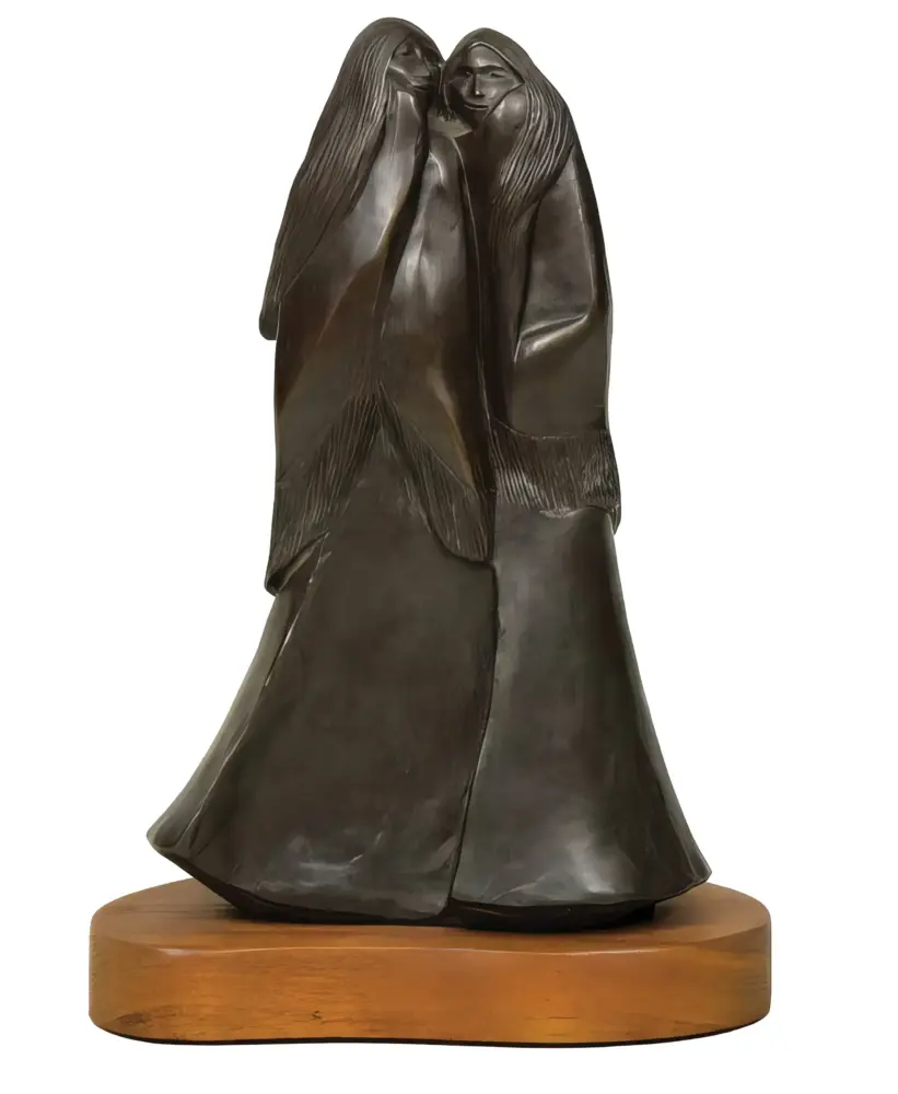 Dark bronze sculpture of two abstract figures embracing, mounted on a circular wooden base.