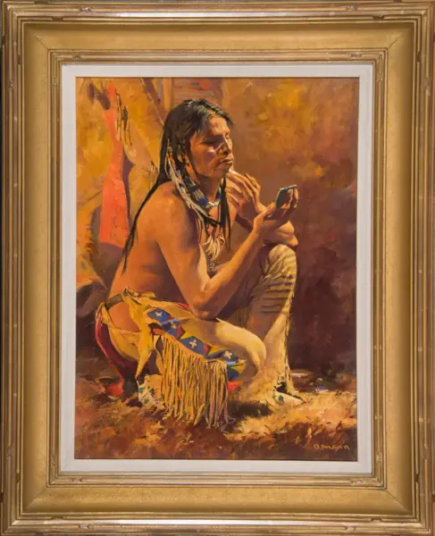 Portrait of a Native American man sitting on the ground, applying makeup while looking into a small mirror, wearing fringed buckskin and bead jewelry.