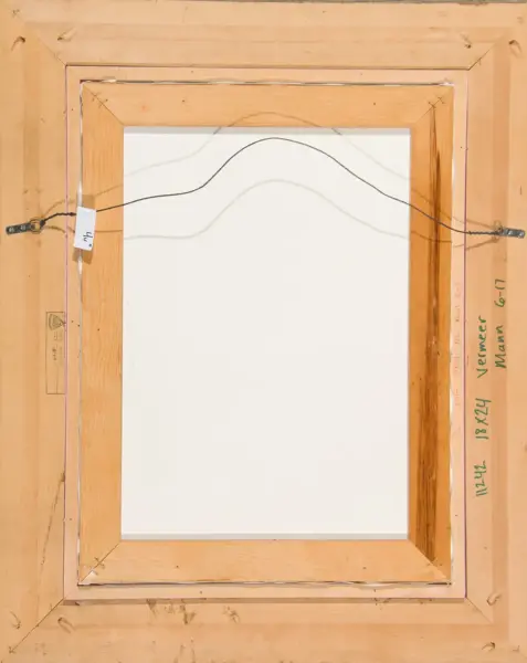 Back of a framed canvas showing a hanging wire and wooden stretcher bars with labels on the sides