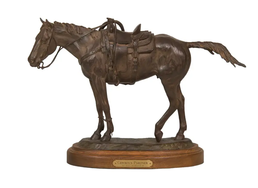 Bronze statue of a horse with saddle and reins on a wooden base, titled 'Cowboy's Partner'.