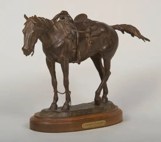 Bronze sculpture of a saddled horse standing on a wooden base, titled Cowboy's Partner.