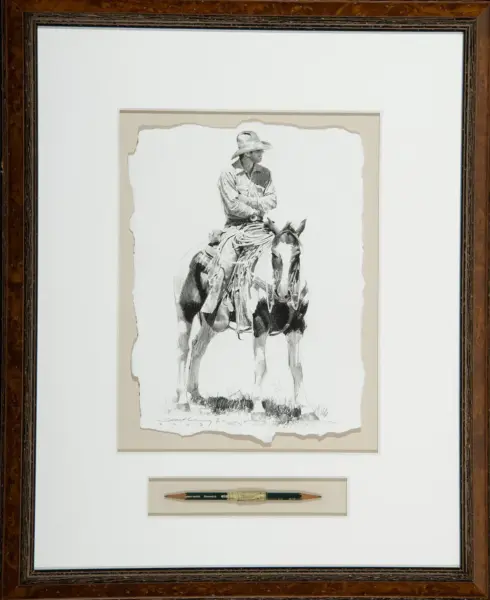 Framed black-and-white sketch of a cowboy in a hat riding a horse, mounted on a cream mat with a pencil displayed below the art