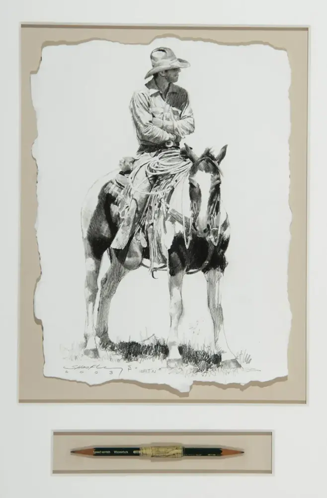 Framed black-and-white sketch of a cowboy in a wide-brimmed hat riding a horse, mounted on a beige mat; a pencil is displayed in a separate frame below.