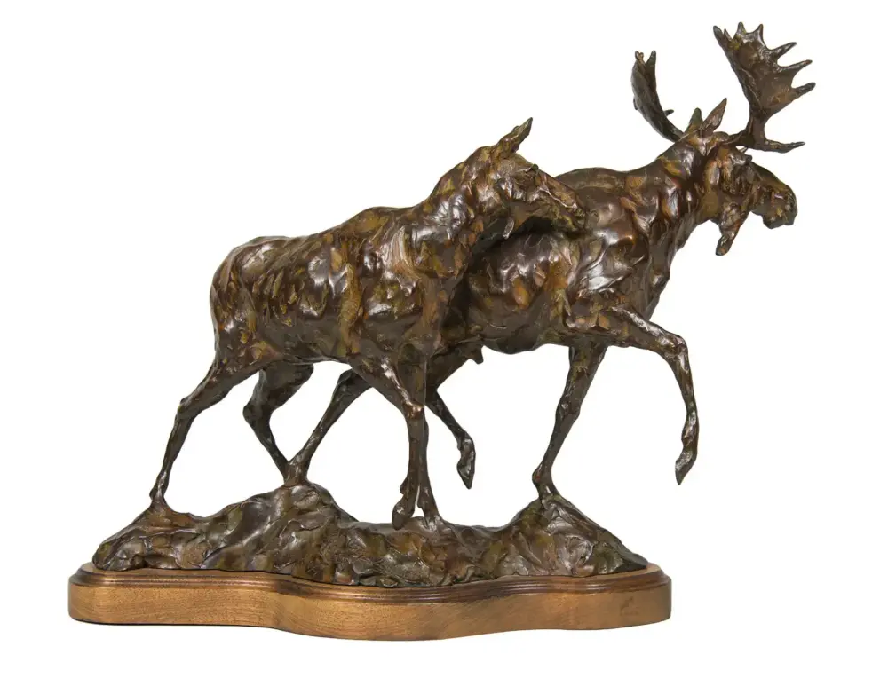 Bronze sculpture of two moose running on a rocky base with a wooden plinth