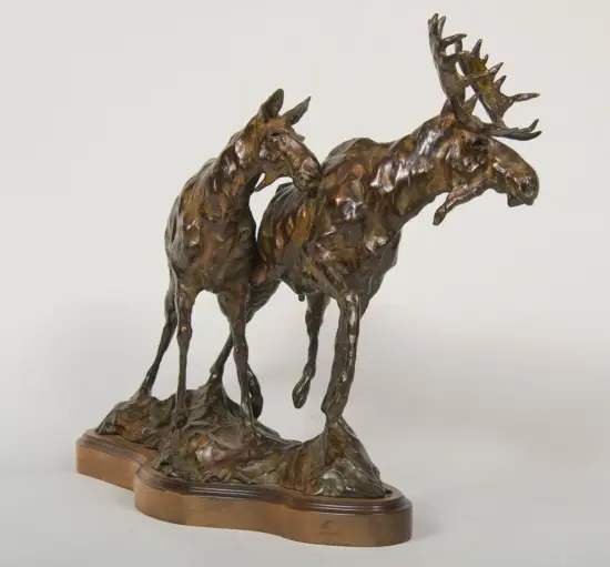 Bronze sculpture of two moose with intertwining necks and antlers, mounted on a wooden base.