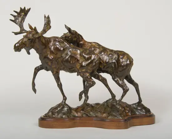 Bronze sculpture of two moose locking antlers as they clash, mounted on a wooden base