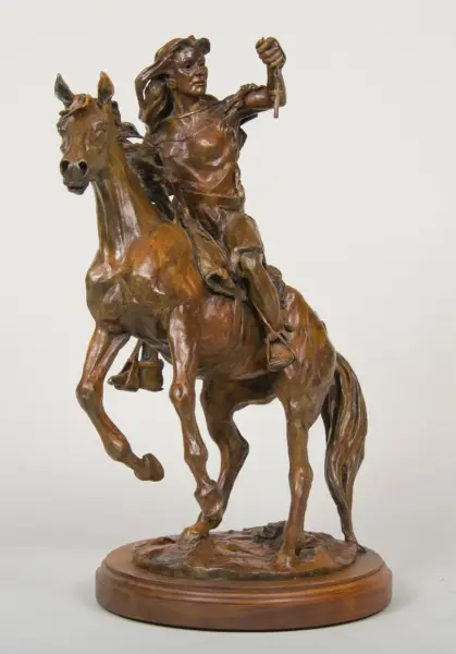 Bronze statue of a Native American rider on a rearing horse, arm raised with a dagger, mounted on a wooden base.