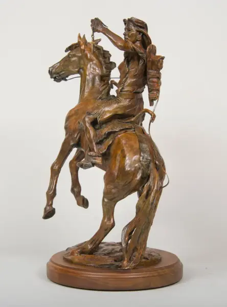 Bronze sculpture of a man on a rearing horse, raising an object above his head, with a quiver on his back, mounted on a wooden base