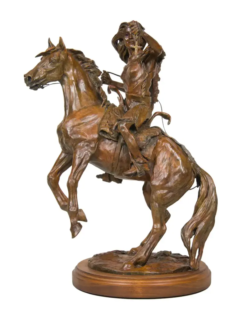 Bronze statue of a Native American rider on a rearing horse, mounted on a wooden base.
