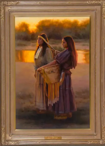 Framed painting of two women in 19th‑century dresses by a river at sunset, one guiding a woven loom or basket between them.