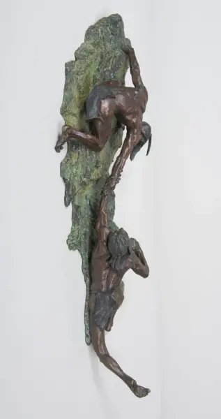 Bronze sculpture of a climber gripping a rough green rock, reaching upward while another figure climbs below.