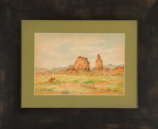 Framed desert landscape painting with two tall rock formations and a lone rider on horseback in the foreground.