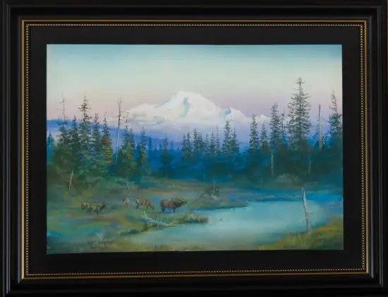 Framed landscape painting showing a snow-capped mountain behind a dense evergreen forest and a small herd of elk by a calm lake.