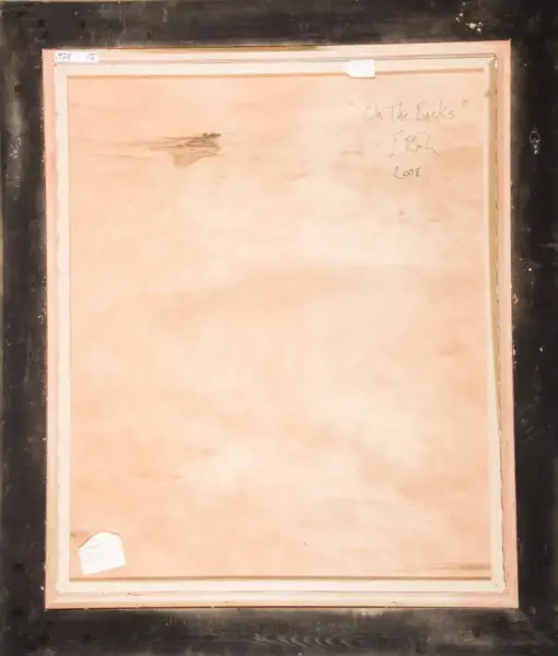 Back of a framed canvas with a pale pink lining; handwritten title 'On The Rocks' and signature 'J. Rick' with '2008' noted on the wooden back, plus small labels on the edges.