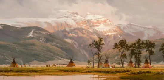 Teepees pitched on a grassy plain with snow-covered mountains in the background from a wide valley viewpoint.