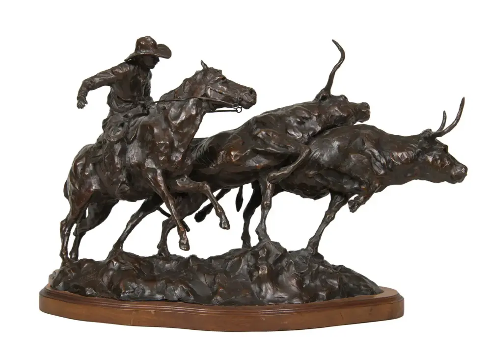 Bronze sculpture of a jockey on a racing horse leading a group of sprinting horses, mounted on a wooden base.