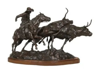 Bronze sculpture of a jockey on a racing horse leading a group of sprinting horses, mounted on a wooden base.