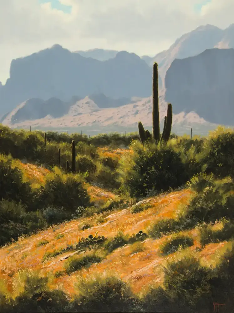 Desert landscape with a tall cactus in the foreground and rugged mountains in the distance under a blue sky, sunlit vegetation around.