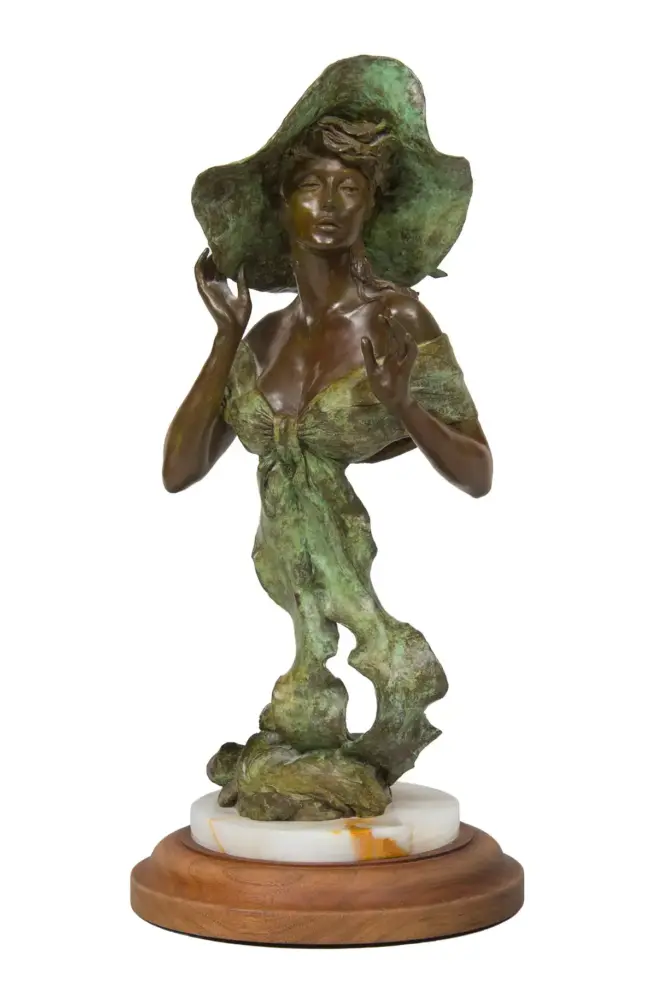 Bronze-green statue of a woman in a large hat, wearing a tied dress, standing on a rocky pedestal atop a wooden base