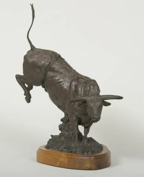 Bronze sculpture of a long-bodied dog in mid-stride on a wooden base.