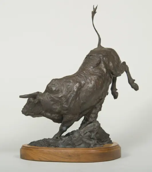 Bronze sculpture of a dog in mid-leap atop a wooden circular base