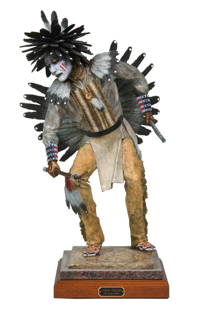 Life-size sculpture of a Native American man in a feathered headdress and traditional regalia, posed on a wooden pedestal.