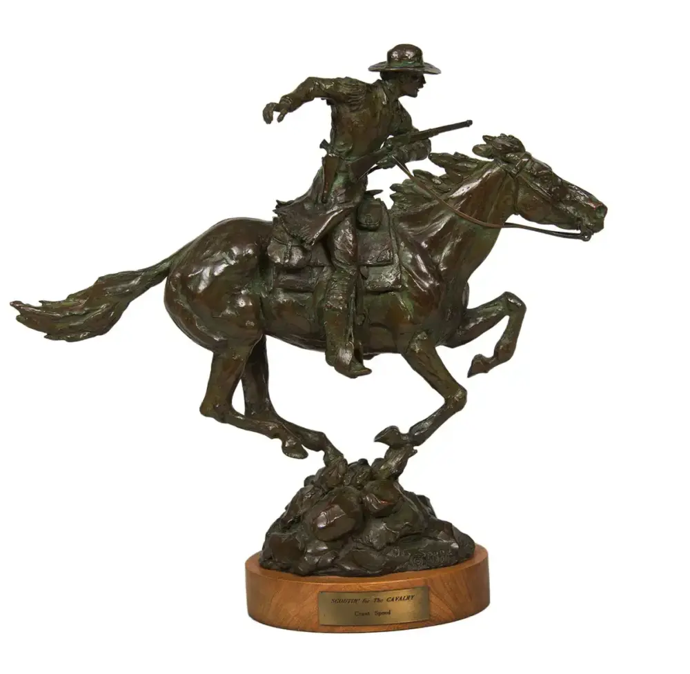 Bronze equestrian sculpture of a rider on a rearing horse leaping over rocks on a wooden base