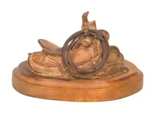 Wooden carved statue of a reclining animal with a rope coiled around its neck on a round pedestal.