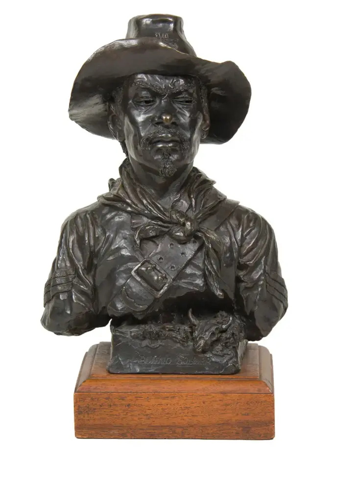 Bronze bust of a Buffalo Soldier wearing a wide-brimmed hat and scarf, mounted on a wooden display base.