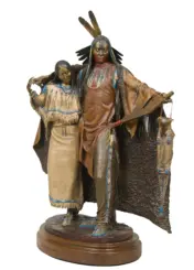 Bronze-toned sculpture of a Native American man in a feathered headdress with a woman beside him, both in fringed beadwork attire on a round pedestal