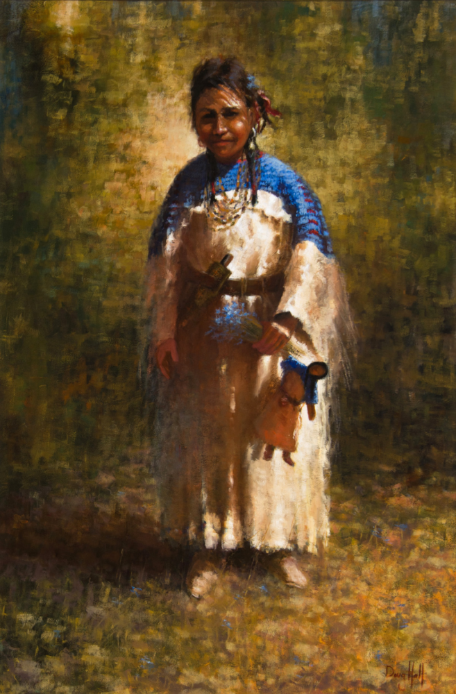 A woman in a blue shawl and white dress stands outdoors in a grassy field, wearing layered beads and carrying a small bag or pouch.