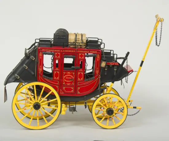 Antique red and black stagecoach with ornate gold trim and bright yellow wheels, displayed against a plain background.